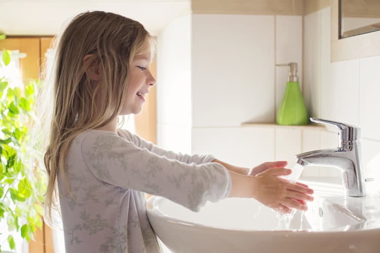Ein Mädchen wäscht sich die Hände mit Wasser