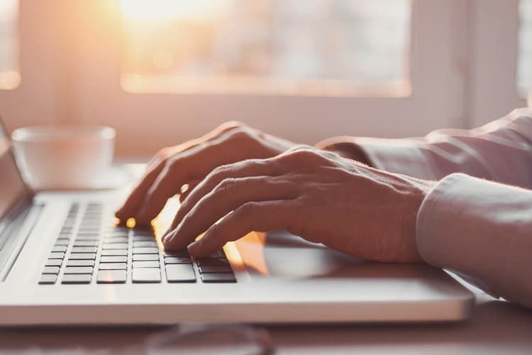 Hände tippen auf einer Laptop-Tastatur