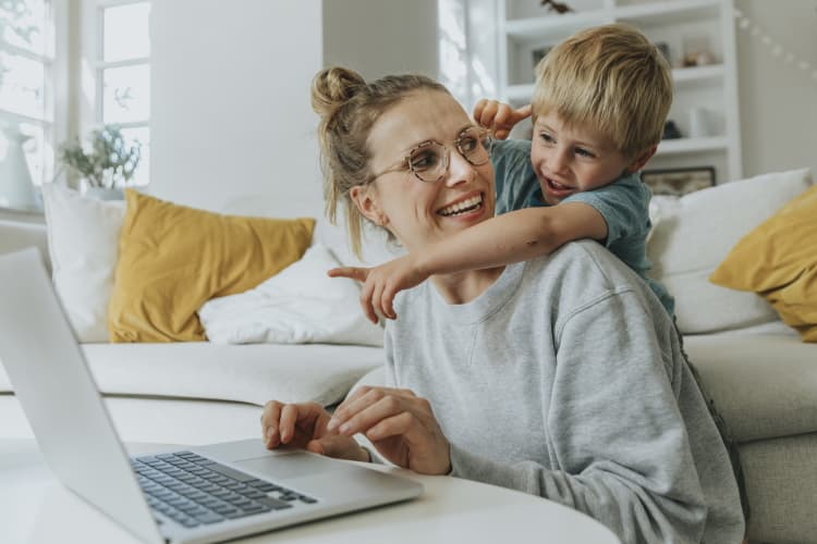 Ein Junge zeigt freudig auf den Laptop seiner Mutter